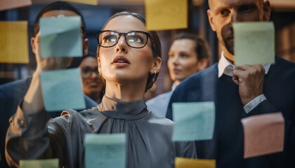 Diverse business team collaborating on project with sticky notes on glass wall. Concept for strategic planning, brainstorming session and problem-solving