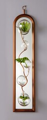 Vertical wall decor featuring glass orbs and greenery in a copper frame design