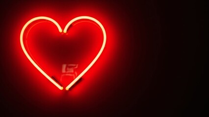 Vibrant red neon heart sign illuminating a dark background with subtle glow