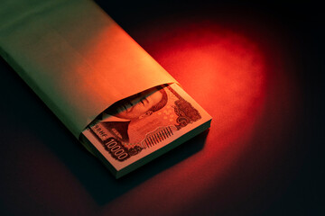 一万円札の札束と封筒が赤い光に照らされる金融コンセプト