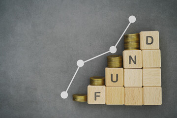 FUND text on wooden cube block with stack of coins above and graph line for business investment, strategy concept