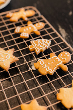 Wire cooling rack sitting on dark counter holding gingerbread star tree and human shapes iced white