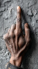 African American Man's Hand Displaying Middle Finger on Textured Gray Concrete Wall Background
