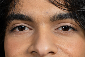 Single man showcasing skin texture brows under soft shadows in portrait studio with dark backdrop