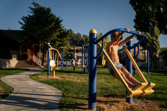 A young boy in bathing suit plays on swing at playground
