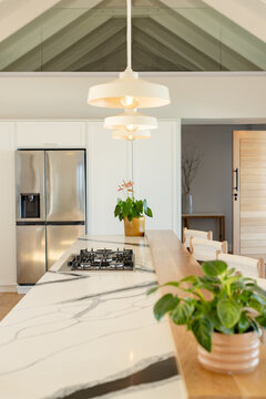 White marble island featuring black veins, hosting gas cooktop and pendant lights in modern kitchen