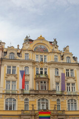 Fototapeta premium ornate yellow facade with pride flag, decorative gables and sculpted balcony framed by vertical national