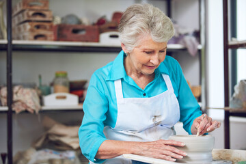 Pottery, clay and old woman with tools in studio for shape, handcraft and creative design. Wheel, ceramic art and happy senior person in workshop for hobby, mold and potter sculpting in retirement