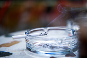Close-up of a burning cigarette in an ashtray.