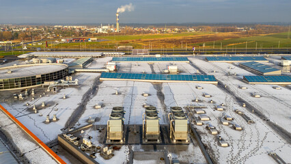 Snow covered roof of logistics center with visible technical infrastructure and industrial rooftop installations © Adam