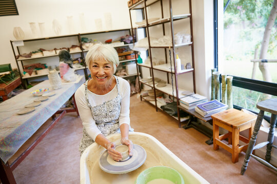 Portrait, old woman and smile at pottery workshop with apron for ceramics, retirement activity or fun. Happy, senior person and pride in art studio for clay design, creative hobby and handmade craft. - Powered by Adobe