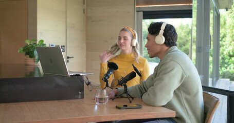 Diverse coworkers approaching studio table, picking up headphones, testing mics, starting podcast