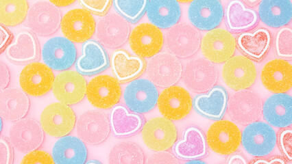 Colorful gummy candy on a pink background.