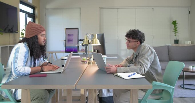 Male coworkers grabbing coffee before collaborating to resolve code issue at lounge with laptops
