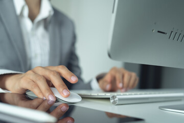 Business woman, hand clicking on wireless computer mouse. Businesswoman online working on desktop computer at office, internet research for business project, closeup