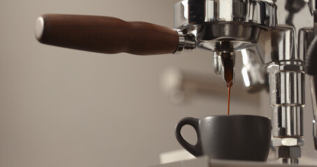 espresso pour from single spout portafilter into black cup