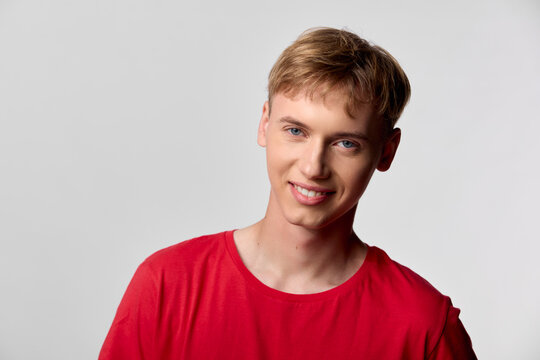 Smiling young man in a red shirt stands against a neutral background, conveying casual confidence, approachable style, and positive energy for lifestyle, fashion, or corporate headshots in modern