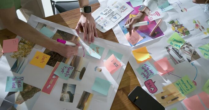 On start two hands are sketching arrows and arranging sticky notes on wooden board for planning
