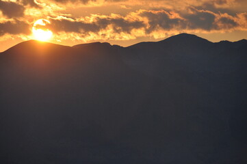 Stunning sunset casts golden light over mountain peaks in the evening sky