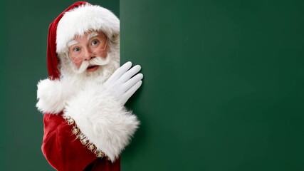 Santa in traditional red coat and fluffy gloves stands by green wall with hand on beard suggesting thoughtful christmas moment perfect for reflective holiday messages and branding