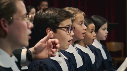 Children's choir gestures with passion during choral performance on stage in concert hall
