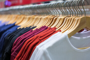 Colorful shirts hang on hangers in a clothing store, ready for sale.