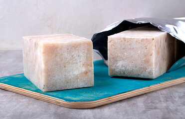 Frozen portioned minced white fish on turquoise wooden board. Fresh seafood ingredient in the form of pressed briquettes