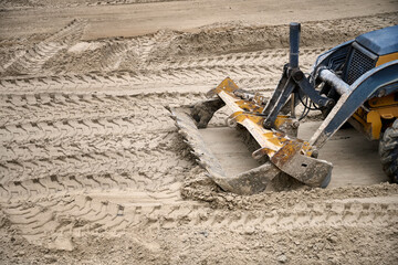 Top view of bulldozer works at the construction site of a new home, leveling sand for the foundation.