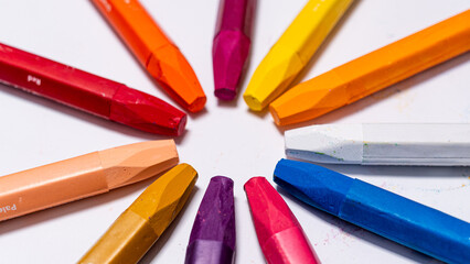 Close-up shot of colorful crayons forming a rainbow ring with scattered pigment dust.