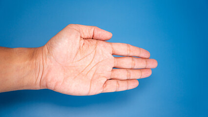 A close-up view of an open palm facing upward on a smooth blue surface.
