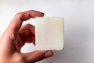Hand holding a white bar of soap. Personal hygiene and skincare. Natural cosmetic for body wash. Close up studio shot with copy space.