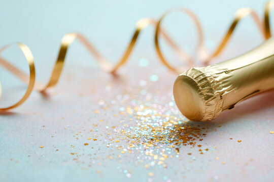 Close-up of gold champagne bottle neck with glitter and ribbon. Festive party background for New Year or birthday celebration. Copy space for text