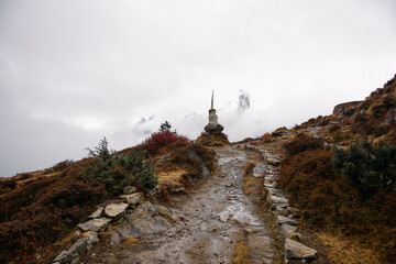 Fototapeta premium Nepal, Himalayas - October 30, 2025: Rocky path leads to stone structure on a foggy mountain in the Himalayas during early morning hours