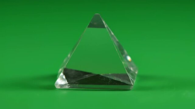 Isolated perfect geometric crystal prism slowly rotating against a bright solid chroma key green screen background ready for visual effects and easy compositing blank object, simple, high quality