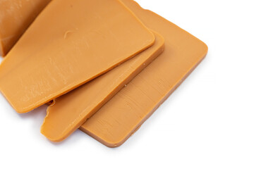 Traditional Norwegian Brunost cheese block and thin slices on a clean white background, showcasing the caramel-brown texture of this iconic Scandinavian dairy product