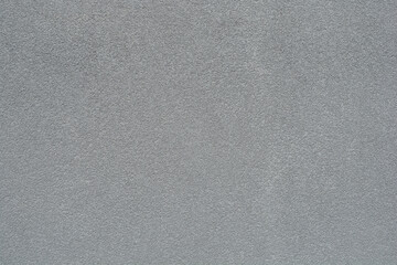 A tight, abstract background shot of a wall with a very fine-grained, uniform dark gray rough plaster (stucco) texture