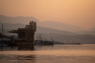 Serene harbor silhouette at dusk with mountain ranges and still water