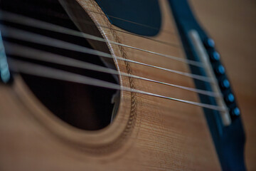 Obraz premium A sharp close-up photograph of an acoustic guitar highlighting its strings, wood texture, and craftsmanship. Ideal for music, instruments, creativity, and artistic product themes.