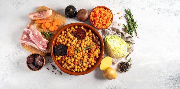 Ingredientes del cocido madrile&ntilde;o en composici&oacute;n cenital, sobre una mesa blanca, tradici&oacute;n culinaria y sabor de la cocina espa&ntilde;ola a fuego lento con espacio para texto y publicidad editorial