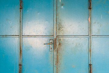 Rusty Blue Metal Door Close-up with Vertical and Horizontal Lines and Handle.