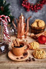 Hot coffee in clay cup with star anise on old wooden board with homemade cookies. Christmas composition with festive decor.