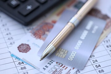 Credit card and pen with russian ruble currency money bills banknotes on calculations document background. Business, financial operations and accounting in Russian Federation