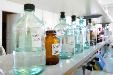 Collection of glass bottles filled with various chemicals in a laboratory setting during daylight...