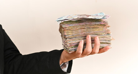 hand firmly hold wide stack of cash, symbolizing large earnings, savings, market opportunities. thickness of banknotes shows financial scale. Person presents heavy bundle of paper currency,
