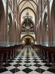 Ornate church interior with tall arches, chandeliers, and checkered floor. Grand Church Interior With Arched Ceilings and Chandeliers.