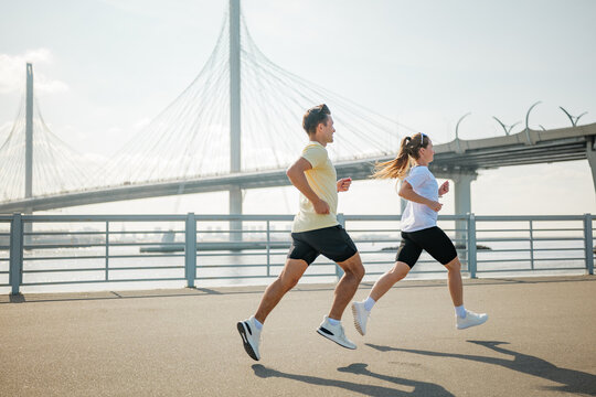 People run near a bridge over the water - Powered by Adobe