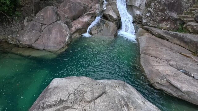 Khe Van Waterfall in Binh Lieu, Quang Ninh, Vietnam, showcasing cascading streams flowing over layered rock formations into a clear turquoise pool.