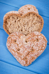 Fresh homemade wholegrain bread in shape of heart for breakfast. Blue boards