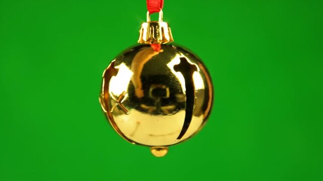 A shiny gold Christmas ornament hangs from a red string against a seasonal green screen background.