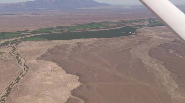 The Nazca Desert in Peru and the green river valley from the window of a Cessna airplane